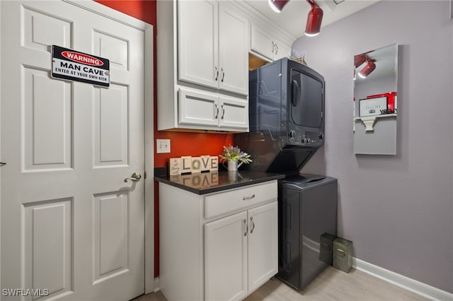 washroom with stacked washer and dryer and cabinets