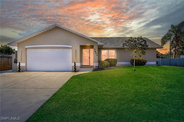 single story home featuring a garage and a lawn