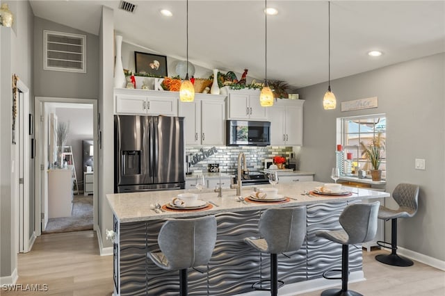 kitchen featuring light stone counters, decorative light fixtures, white cabinets, and appliances with stainless steel finishes