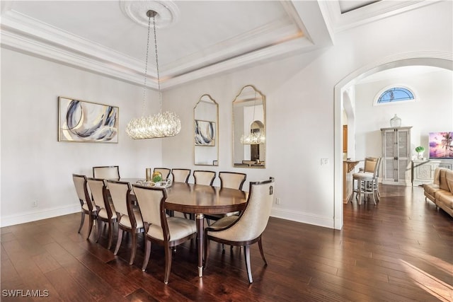 dining area with a chandelier, ornamental molding, a tray ceiling, and dark wood-type flooring