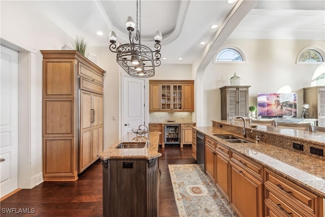 kitchen with dark wood-type flooring, a large island with sink, sink, stainless steel dishwasher, and decorative light fixtures