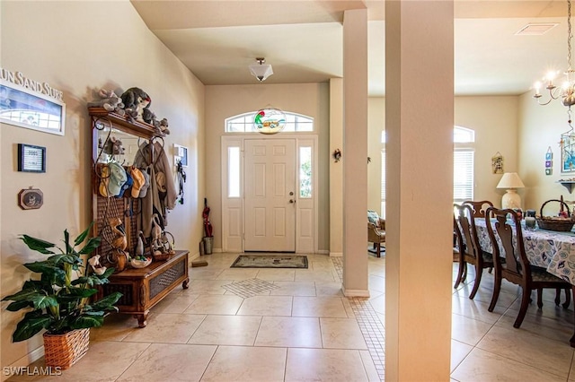 tiled entrance foyer featuring a chandelier and a healthy amount of sunlight