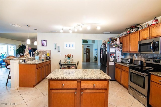 kitchen with backsplash, pendant lighting, a breakfast bar area, a kitchen island, and appliances with stainless steel finishes