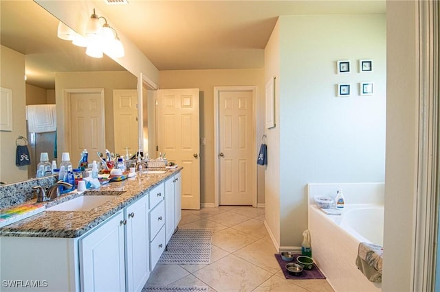 bathroom with tile patterned flooring, vanity, and tiled bath