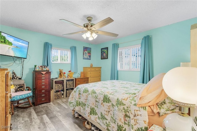 bedroom featuring ceiling fan, a textured ceiling, and light wood-type flooring