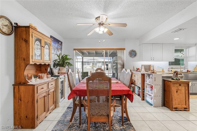 tiled dining room with a textured ceiling, ceiling fan, and sink