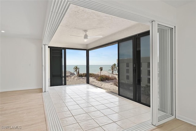 entryway with a textured ceiling, a water view, ceiling fan, and light hardwood / wood-style floors