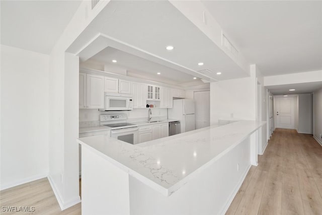 kitchen with white cabinets, white appliances, kitchen peninsula, and light stone counters