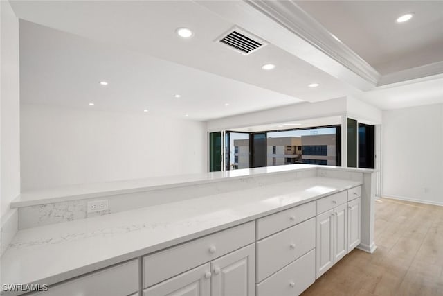 kitchen featuring white cabinets, light stone countertops, and light hardwood / wood-style flooring