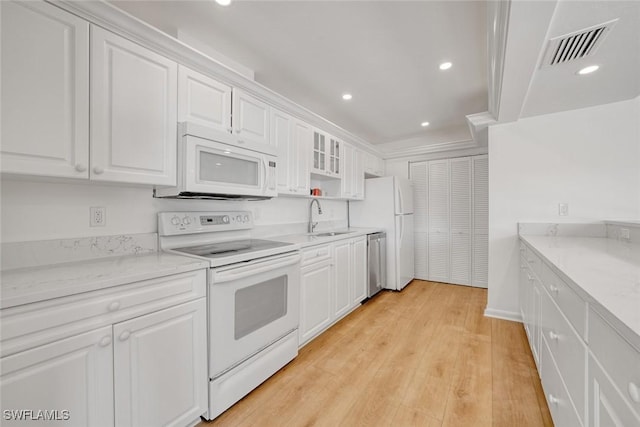 kitchen with white cabinets, light wood-type flooring, white appliances, and sink