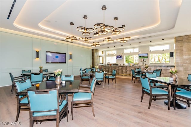 dining room featuring light hardwood / wood-style flooring and a raised ceiling