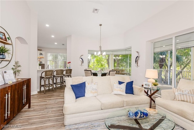 living room with light wood-type flooring and an inviting chandelier