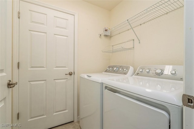 laundry area with washer and dryer and light tile patterned floors