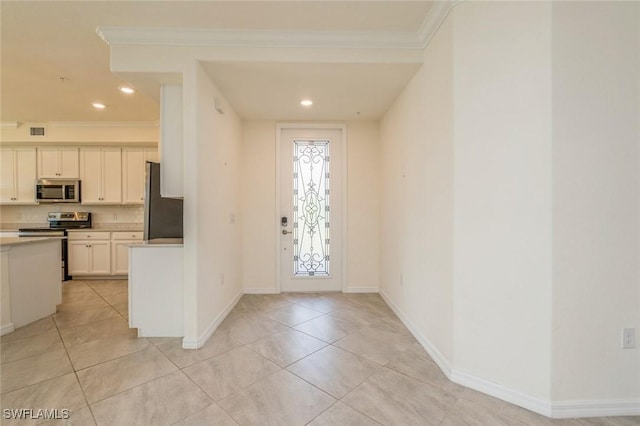 kitchen with stainless steel appliances, light tile patterned flooring, white cabinetry, and crown molding