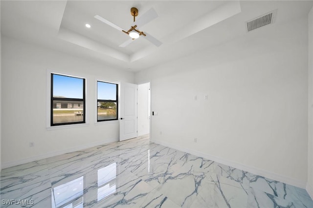 spare room with a raised ceiling and ceiling fan