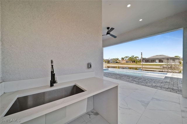 view of patio with ceiling fan and sink