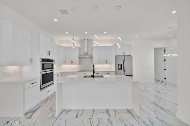 kitchen featuring appliances with stainless steel finishes, sink, wall chimney range hood, a center island with sink, and white cabinets