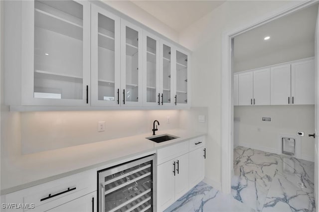 bar with wine cooler, white cabinetry, and sink