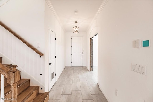 hall with light hardwood / wood-style flooring, ornamental molding, and a notable chandelier