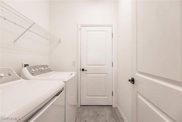 laundry area with independent washer and dryer and light hardwood / wood-style flooring