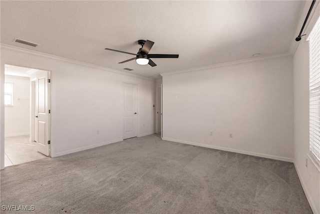 spare room featuring light colored carpet, ceiling fan, and crown molding