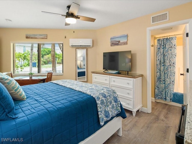 bedroom with ceiling fan, light hardwood / wood-style floors, and a wall unit AC