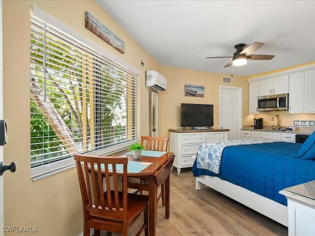 bedroom with sink, a wall unit AC, and light wood-type flooring