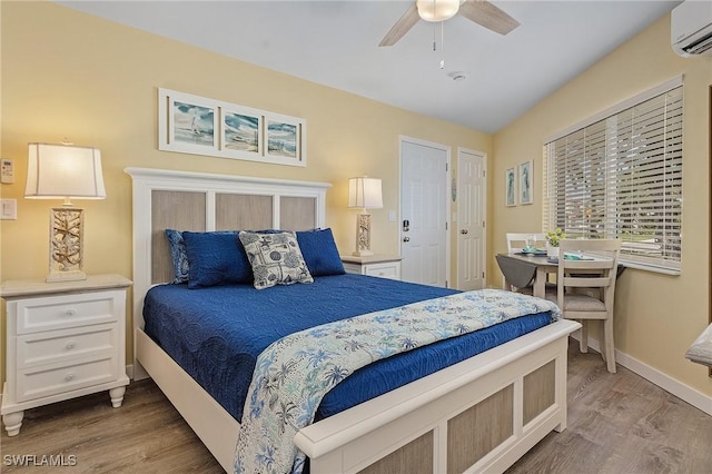 bedroom featuring ceiling fan, hardwood / wood-style floors, and an AC wall unit