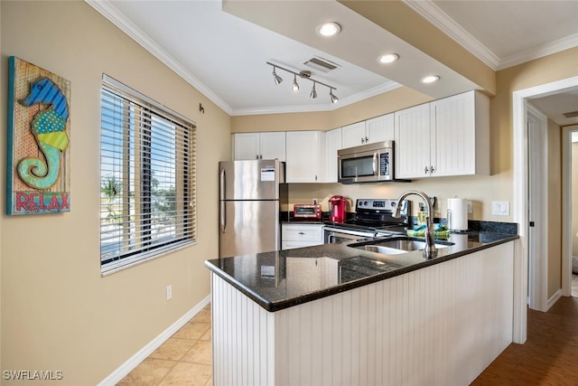 kitchen with crown molding, stainless steel appliances, kitchen peninsula, and white cabinets