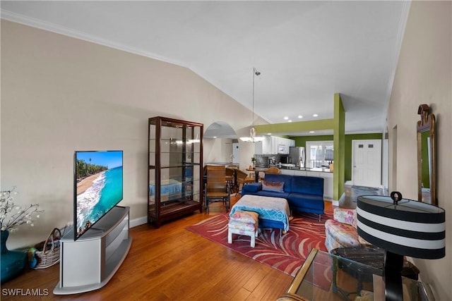 living room featuring hardwood / wood-style flooring, vaulted ceiling, and ornamental molding