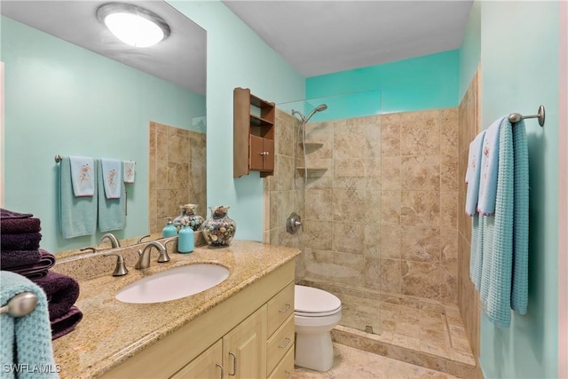 bathroom featuring a tile shower, vanity, and toilet