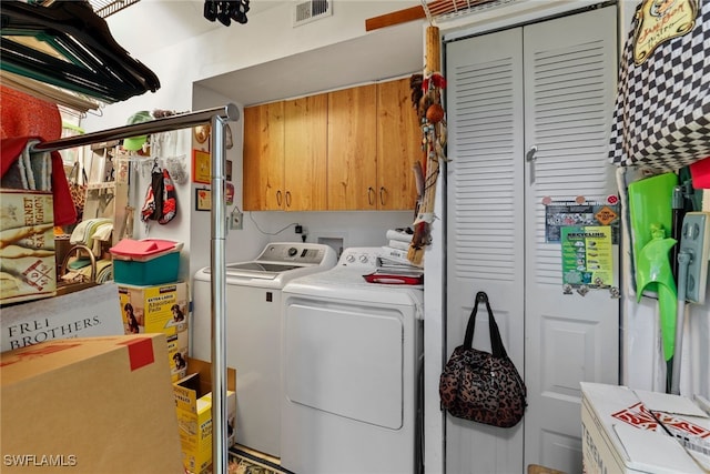 clothes washing area featuring washer and clothes dryer and cabinets