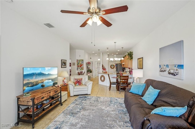 tiled living room with ceiling fan with notable chandelier