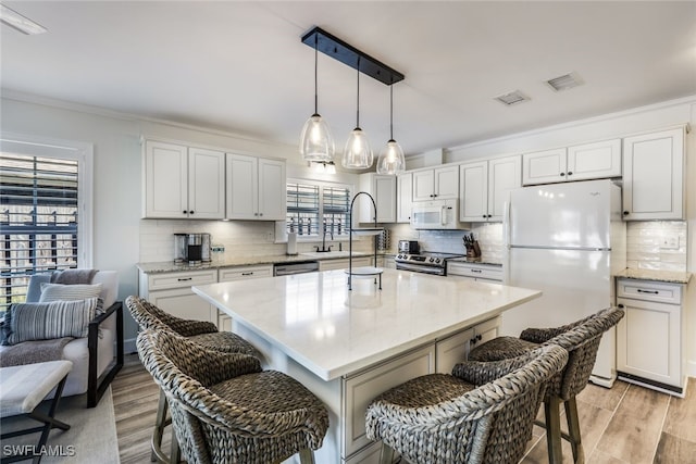 kitchen featuring white cabinetry, a breakfast bar, stainless steel appliances, and light hardwood / wood-style floors