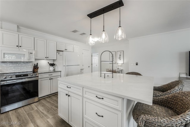 kitchen with a breakfast bar area, white cabinets, and white appliances