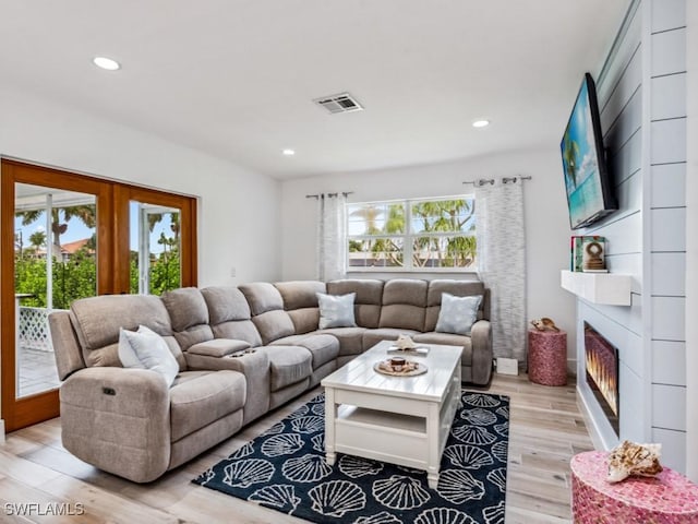 living room featuring a large fireplace, light hardwood / wood-style flooring, and french doors