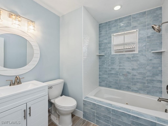 full bathroom with hardwood / wood-style flooring, tiled shower / bath, vanity, and toilet