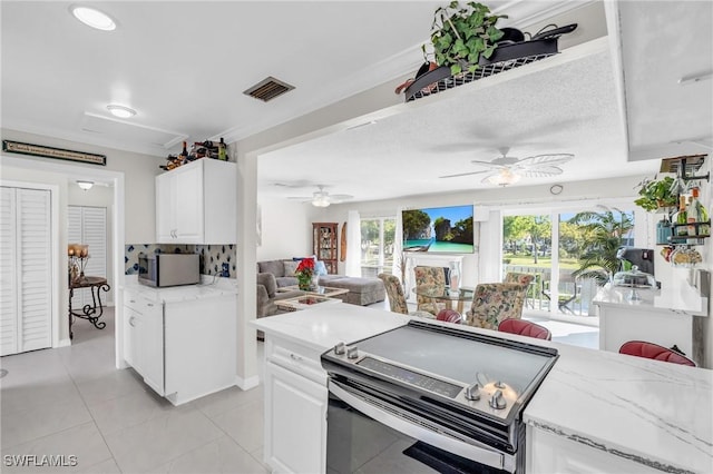 kitchen with white cabinets, decorative backsplash, ceiling fan, light tile patterned floors, and appliances with stainless steel finishes