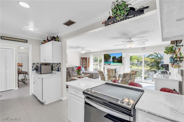 kitchen featuring backsplash, ceiling fan, light tile patterned floors, appliances with stainless steel finishes, and white cabinetry