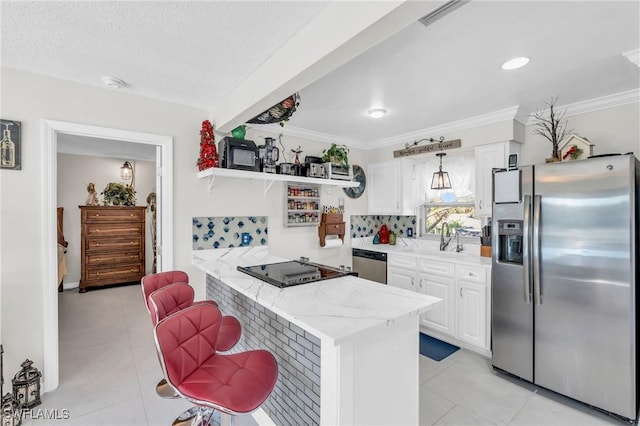 kitchen featuring stainless steel appliances, light stone counters, kitchen peninsula, a kitchen bar, and white cabinets