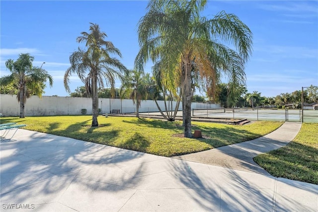 view of community featuring a yard and tennis court