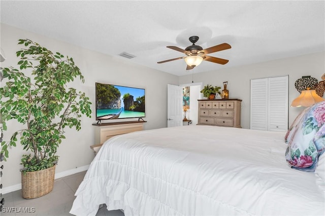 bedroom with ceiling fan, light tile patterned floors, and a closet