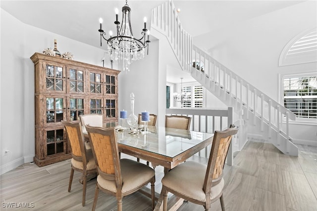 dining area with a towering ceiling, plenty of natural light, and a chandelier