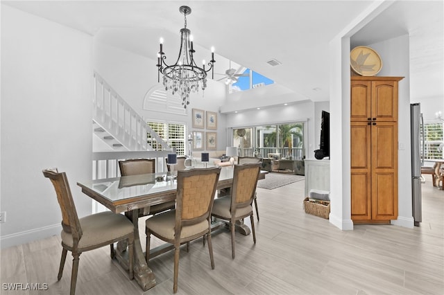 dining room with light hardwood / wood-style floors, high vaulted ceiling, a chandelier, and a healthy amount of sunlight