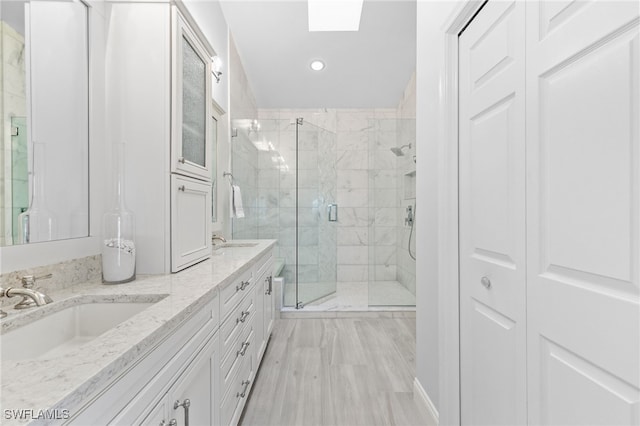 bathroom with walk in shower, a skylight, and vanity