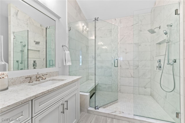 bathroom with a shower with shower door, lofted ceiling, and vanity