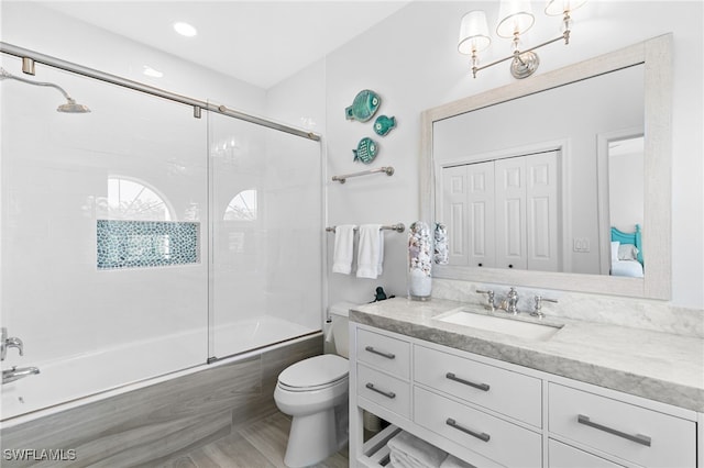 full bathroom featuring enclosed tub / shower combo, vanity, and toilet