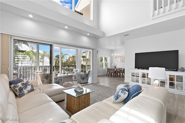 living room featuring a towering ceiling, a chandelier, and hardwood / wood-style floors