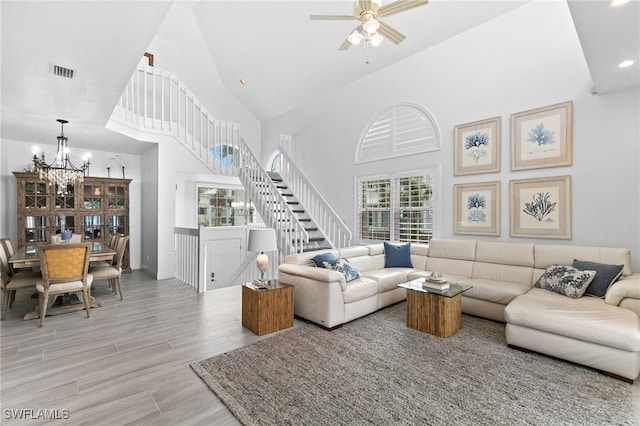 living room featuring high vaulted ceiling and ceiling fan with notable chandelier