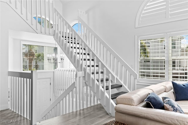 staircase featuring hardwood / wood-style flooring, a high ceiling, and a chandelier